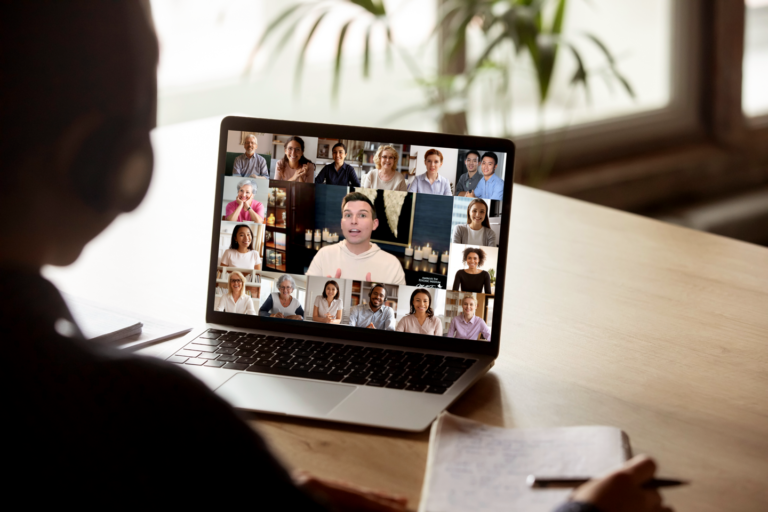 A person participates in a video conference on a laptop, displaying multiple attendees in a grid, including Matt Fraser.